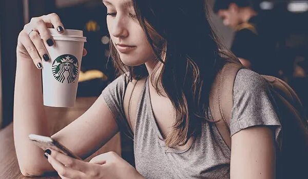 young-girl-using-phone-and-holding-coffee.jpg